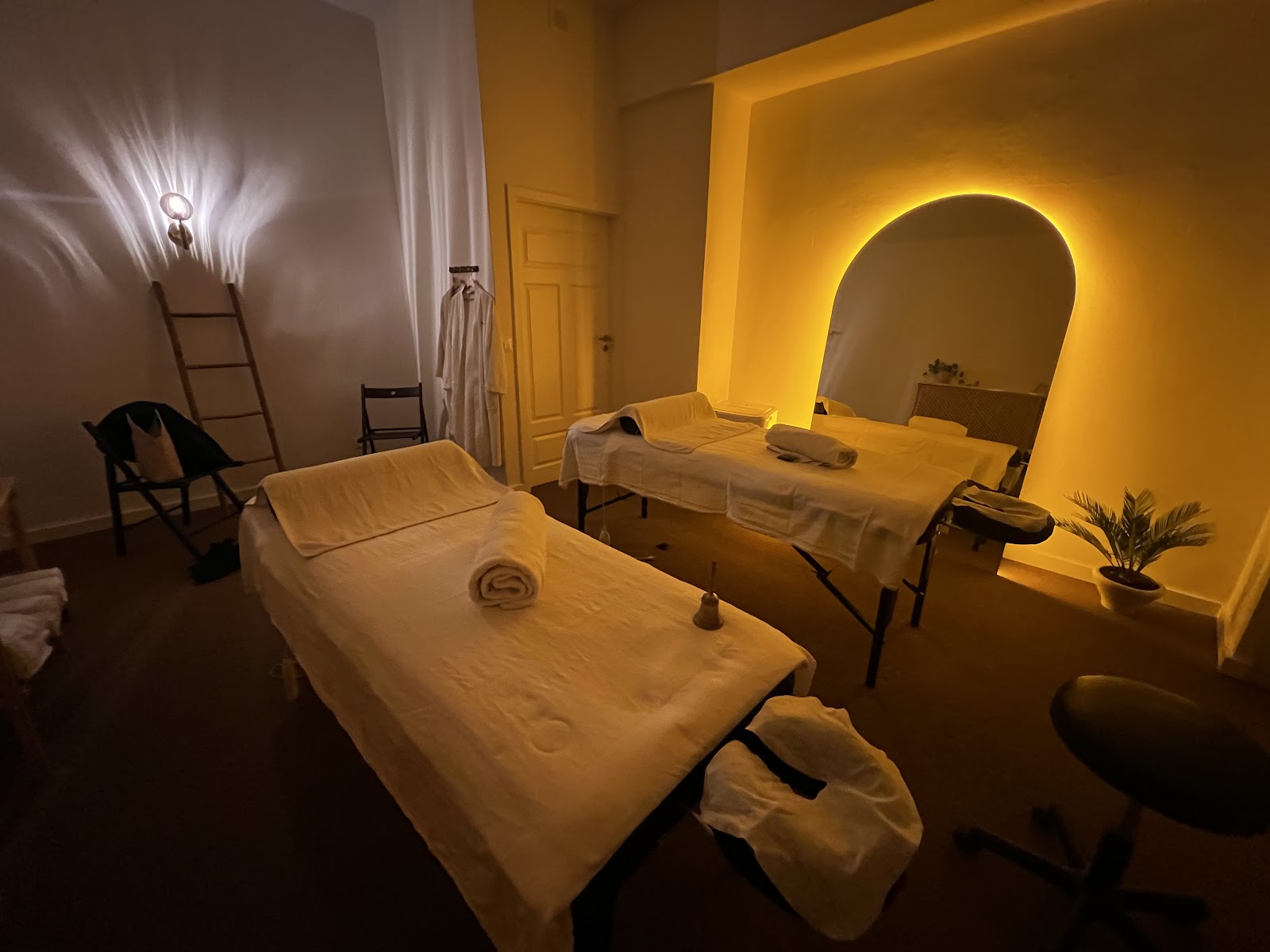 Gabinet o.massage.warsaw w Warszawie — dwie leżanki do masażu pod podświetlanym na złoto łukiem